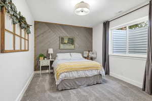 Carpeted bedroom with wooden walls and an accent wall