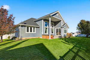Back of house featuring a hot tub, a lawn, a patio area, and a shingled roof
