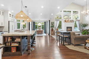 Kitchen featuring a kitchen bar, hanging light fixtures, white cabinets, a chandelier, and glass insert cabinets