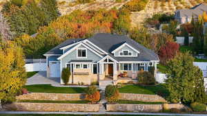 Craftsman-style house with driveway, covered porch, brick siding, roof with shingles, and a garage