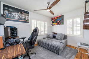 Office space featuring wood finished floors, wainscoting, ceiling fan, and a textured ceiling