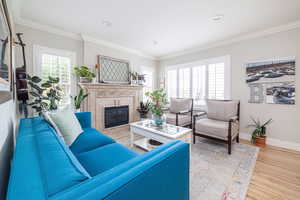Living room with ornamental molding, light wood finished floors, a tile fireplace, and recessed lighting