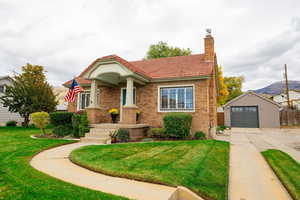View of front of property featuring a chimney, brick siding, an outdoor structure, a tiled roof, and a mountain view