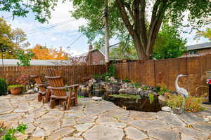 Fenced backyard with a small pond and a patio