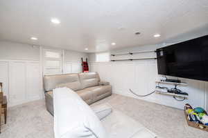 Living area with light colored carpet, a textured ceiling, and recessed lighting
