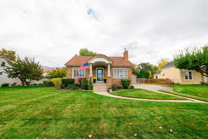 View of front of property with a chimney, a tile roof, and brick siding