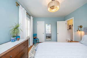 Bedroom featuring multiple windows, light wood-style flooring, and a closet