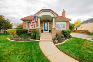 View of front of home featuring a front lawn, a chimney, and brick siding