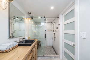 Bathroom featuring vanity, a stall shower, and a textured ceiling