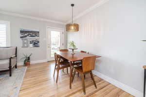 Dining space with light wood finished floors and ornamental molding