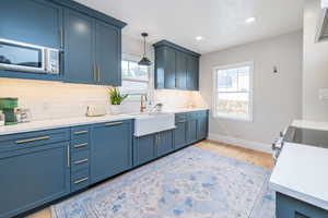 Kitchen with blue cabinets, pendant lighting, light wood-style floors, healthy amount of natural light, and recessed lighting