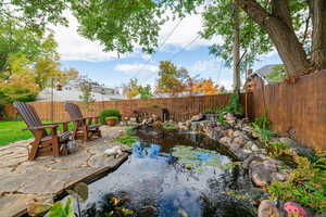 Fenced backyard featuring a patio and a garden pond