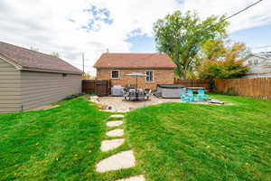 Back of property featuring a patio area, a hot tub, a fenced backyard, and brick siding