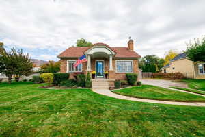 View of front of house with a chimney, a tiled roof, and brick siding