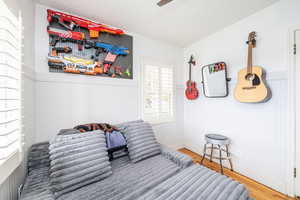 Bedroom with wood finished floors, a ceiling fan, and wainscoting