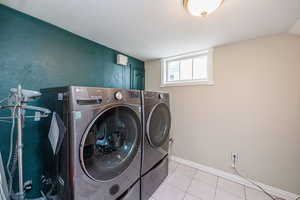 Laundry area with tile patterned floors, a textured wall, and washer and dryer