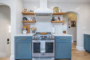Kitchen featuring arched walkways, blue cabinets, and stainless steel electric range oven