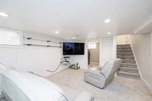 Carpeted living room with a textured ceiling, stairway, recessed lighting, and washer / dryer