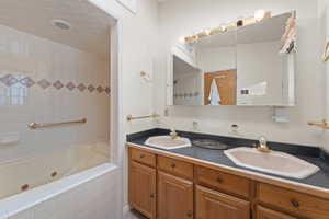 Full bathroom featuring double vanity and a combined bath / shower with jetted tub