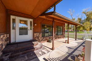 Property entrance featuring stone siding and a patio area