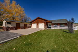 Single story home featuring driveway, stone siding, a front lawn, and an attached garage