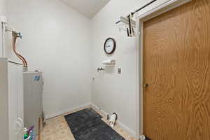 Laundry area with electric water heater and baseboards