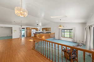 Interior space with vaulted ceiling, ceiling fan, a skylight, a textured ceiling, and a chandelier