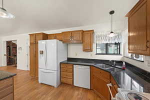 Kitchen featuring hanging light fixtures, white appliances, dark stone counters, and a textured ceiling