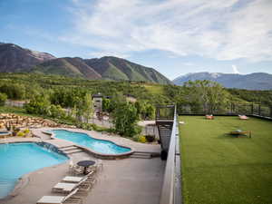 Community pool with a mountain view, a patio area, and a view of trees