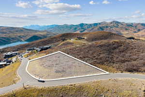 Aerial view of property and surrounding area with property parcel outlined and a mountain backdrop