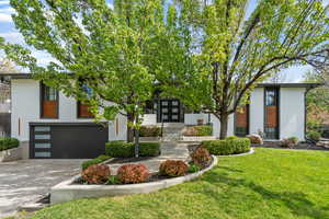 Contemporary house with a front yard, driveway, a garage, french doors, and brick siding
