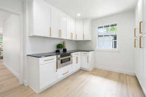Kitchen with stainless steel oven, white cabinets, light wood finished floors, and recessed lighting