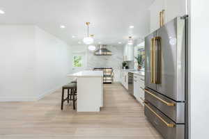 Kitchen featuring high end appliances, white cabinets, a center island, light stone counters, and a breakfast bar