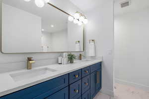Bathroom featuring double vanity and light marble finish floors