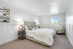 Bedroom featuring carpet floors, a decorative wall, recessed lighting, and a wainscoted wall