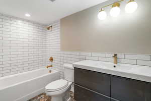 Bathroom with vanity, tile walls, bathtub / shower combination, and recessed lighting