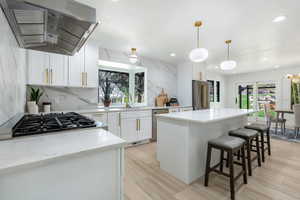 Kitchen featuring exhaust hood, a center island, white cabinets, pendant lighting, and recessed lighting