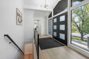 Entrance foyer with light wood-style flooring, a chandelier, and crown molding