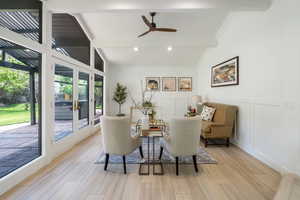Sitting room with a decorative wall, light wood finished floors, ceiling fan, wainscoting, and ornamental molding