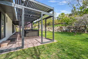 View of grassy yard with a pergola and a patio area