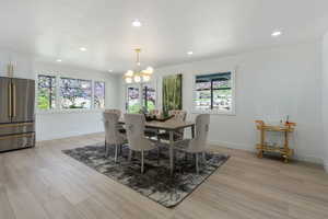Dining space with light wood finished floors, recessed lighting, and a chandelier