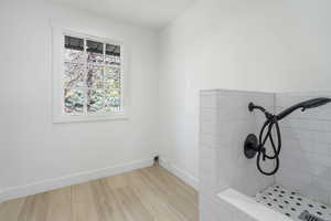 Bathroom featuring light wood-style floors and a tile shower