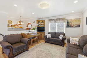 Living room featuring crown molding, light wood-type flooring, and recessed lighting