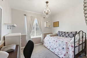 Carpeted bedroom with baseboards and a chandelier