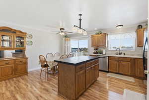 Kitchen featuring brown cabinets, ornamental molding, light wood-type flooring, a kitchen island, and dishwasher