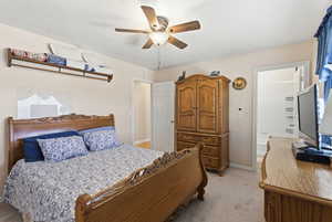 Bedroom featuring light colored carpet, a ceiling fan, and ensuite bathroom