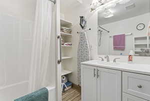Full bathroom with vanity, shower / bath combo with shower curtain, and light wood finished floors
