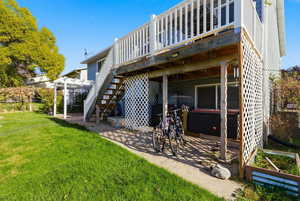 Back of house featuring a lawn, stairs, a deck, and a patio