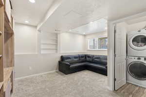 Laundry room featuring a textured ceiling, light carpet, stacked washer / dryer, built in features, and recessed lighting