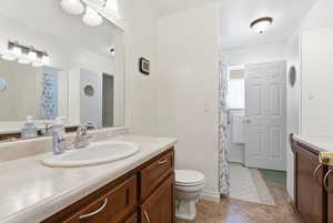 Full bath with vanity, a shower with shower curtain, and light tile patterned floors